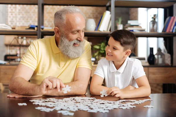 Großvater und Enkel lächeln sich beim Puzzeln an — Stockfoto