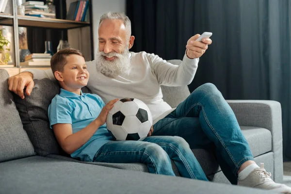 Чоловік вмикає кондиціонер під час перегляду футболу з онуком — стокове фото