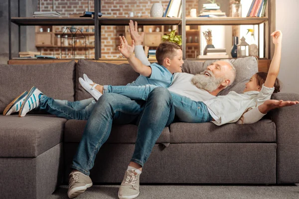 Happy dědeček hrál s jeho vnoučata na gauči — Stock fotografie