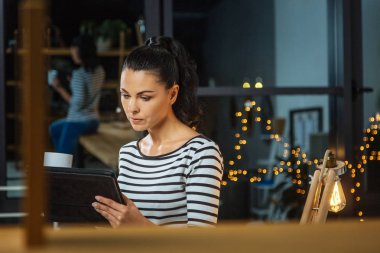 Bir tablet üzerinde çalışan ciddi esmer kadın