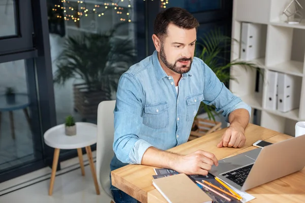 Agradável homem positivo usando um laptop — Fotografia de Stock