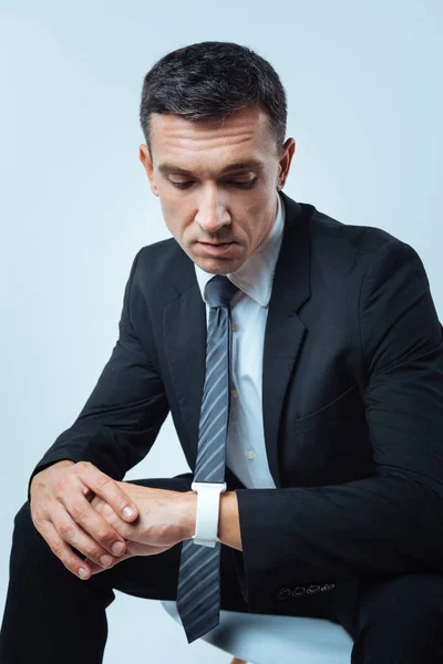 Un serio hombre de negocios ocupado mirando su reloj — Foto de Stock