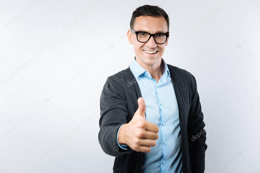 Joyful smart man showing thumbs up gesture