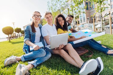 Çimenlerin üzerinde oturan genç insanlar rahat
