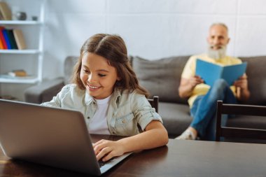 Onun dedesi bir kitap okuma sırasında dizüstü kullanan küçük kız