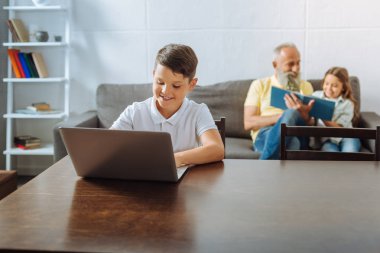 Dedesi ve kız kardeşi birlikte okuma sırasında dizüstü kullanarak çocuk