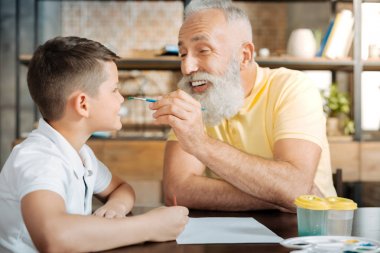 Oynak dedesi torunları burnuna bir suluboya nokta koyarak