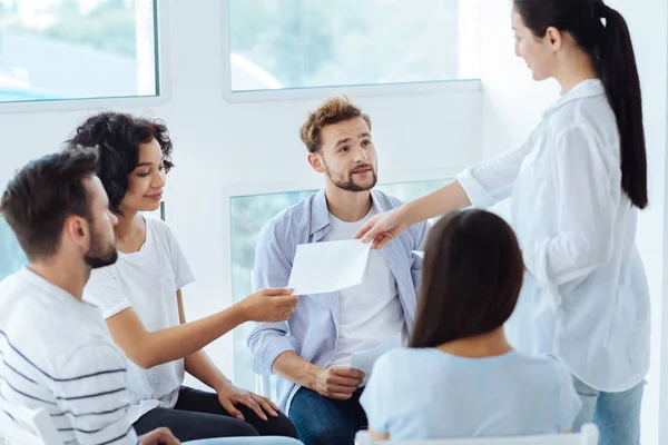 Terapeuta de grupo profesional que da hojas de papel — Foto de Stock