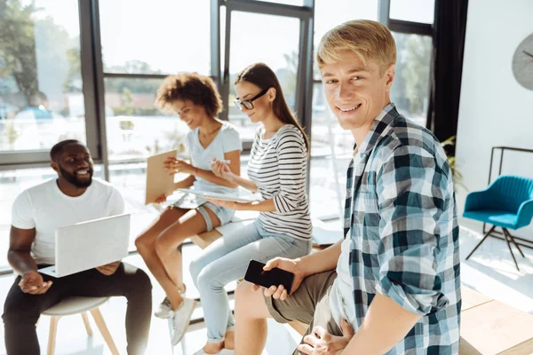 Jovem positivo descansando com seus companheiros de grupo — Fotografia de Stock