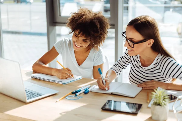 Positieve vrouwelijke studenten doen hun huiswerk — Stockfoto