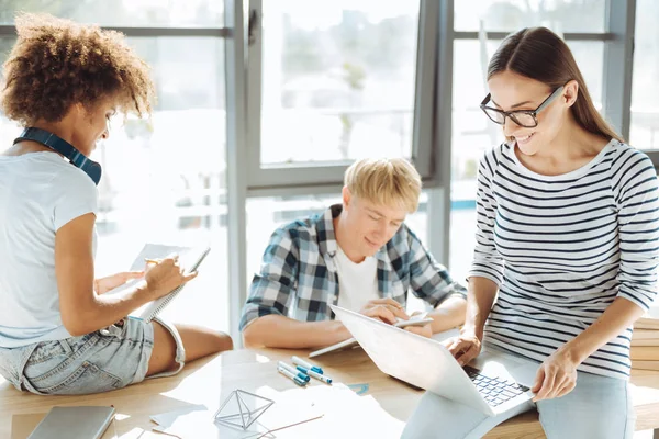 Wanita muda yang positif menggunakan laptopnya — Stok Foto