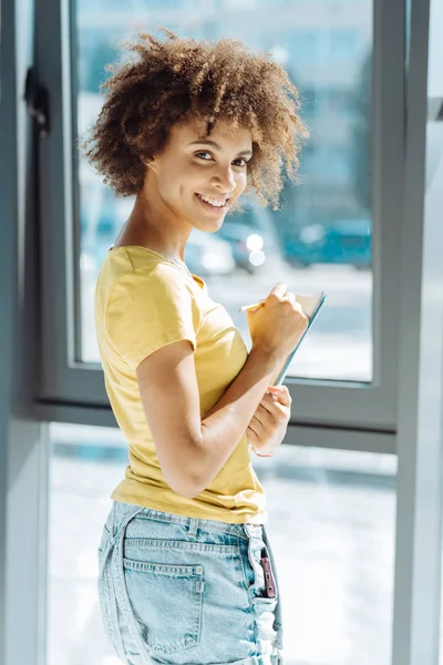 Vrolijke jonge afro Amerikaanse student maken van notities — Stockfoto