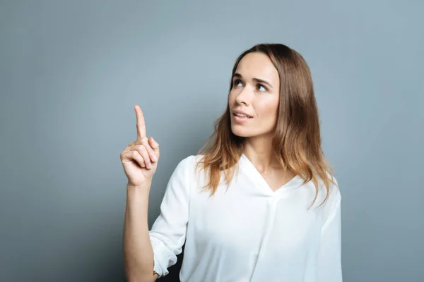 Attraktive junge Frau zeigt mit dem Finger nach oben — Stockfoto
