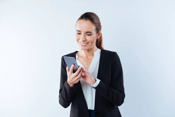 Mujer feliz positiva mirando la pantalla de su teléfono inteligente — Foto de Stock