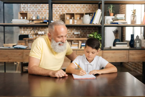 Cuidar abuelo ayudar a su nieto con la asignación en casa — Foto de Stock