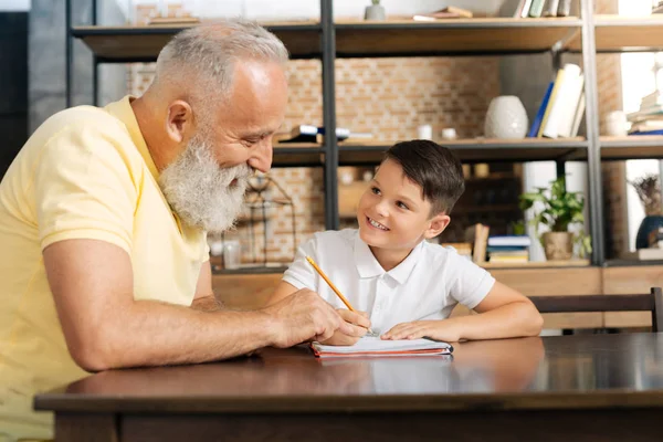 Caring grandfather giving tips on grandsons home assignment — Stock Photo, Image