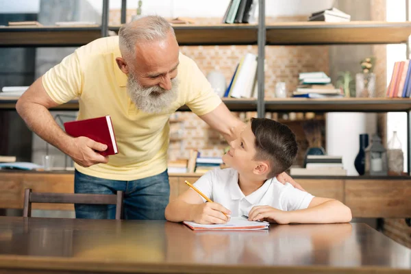 Zorgzame opa zijn kleinzonen vooruitgang in huiswerk controleren — Stockfoto
