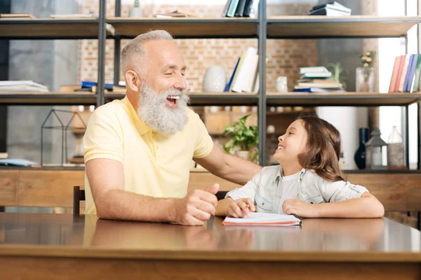 Grandfather and granddaughter laughing happily at the table — Stock Photo, Image