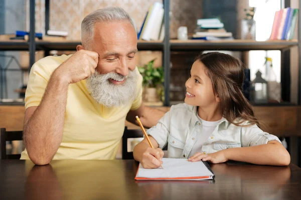 Amar al abuelo echando un vistazo a sus nietas tarea — Foto de Stock