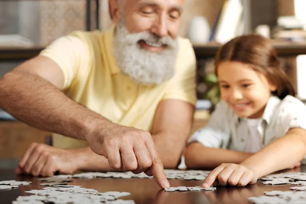Grandfather and granddaughter joining two jigsaw puzzle pieces — Stock Photo, Image