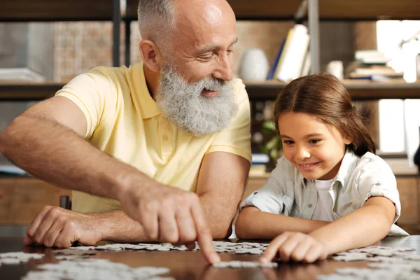 Adorable niña montando rompecabezas con su abuelo — Foto de Stock