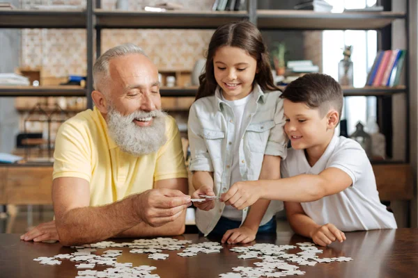 Broers en zussen en hun grootvader toetreding tot drie jigsaw puzzel stukjes — Stockfoto