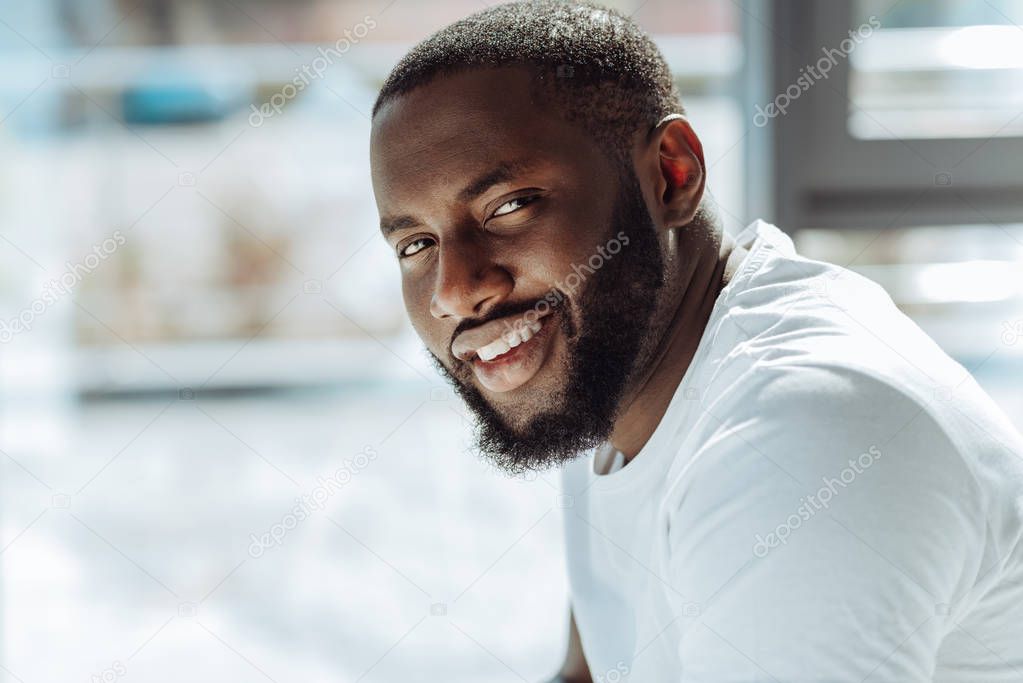 Joyful handsome afro american man smiling in front of the camera