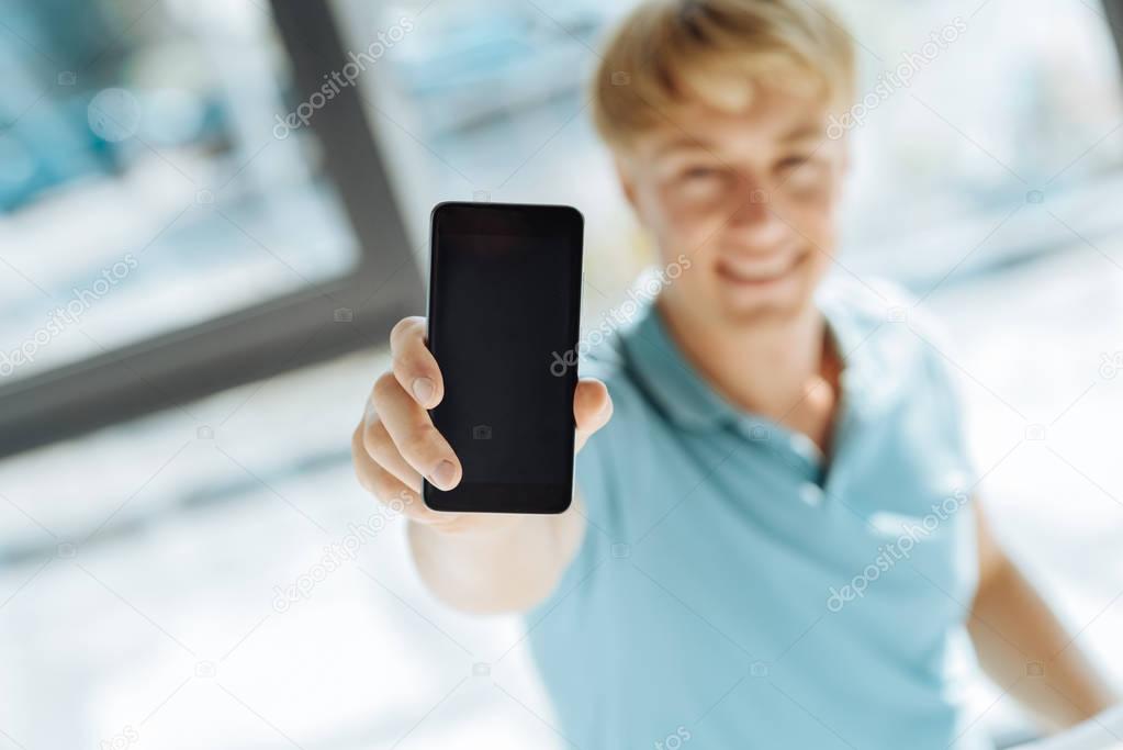 Close up of modern smart phone in hands of a handsome young man