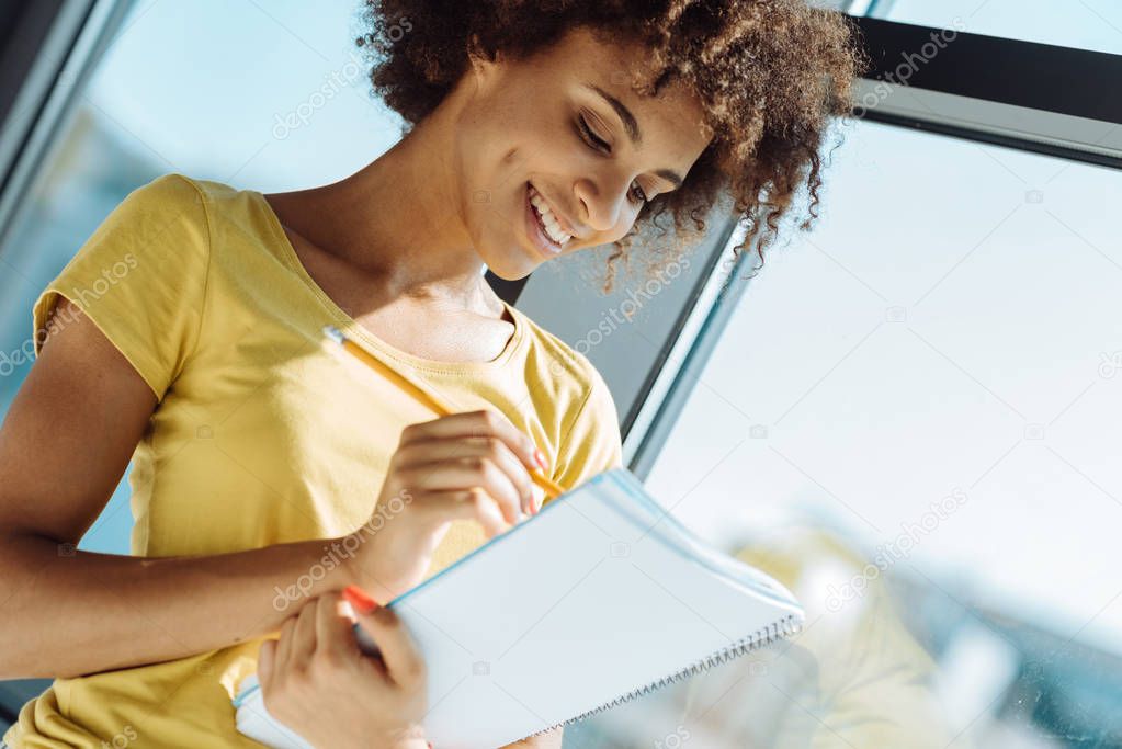 Close up of positive young afro american woman making notes