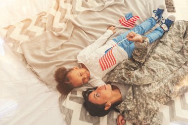 Kamuflaj ve kızı yatakta yatarken anne