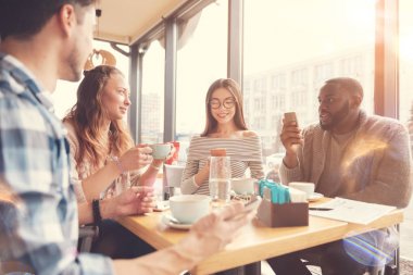 Kafede oturan neşeli uluslararası öğrenciler