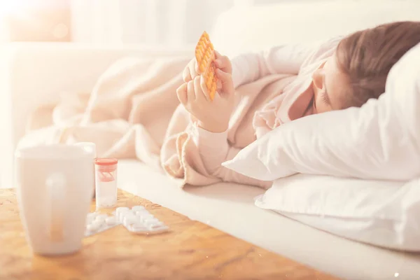 Sick girl looking at orange plates with tablets — Stock Photo, Image