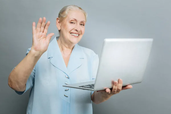 Positive mature female waving her right hand — Stock Photo, Image