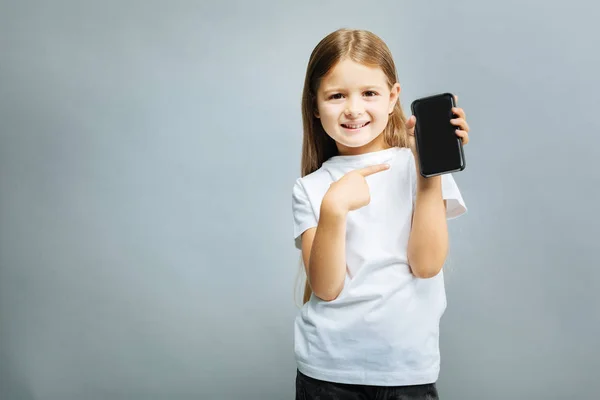 Cheerful kid pointing at her telephone — Stock Photo, Image