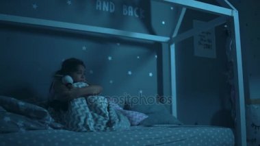 Geceleri yatağında oturup biraz korkmuş bir kız