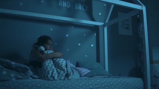 Pequena menina assustada sentada em sua cama à noite — Vídeo de Stock