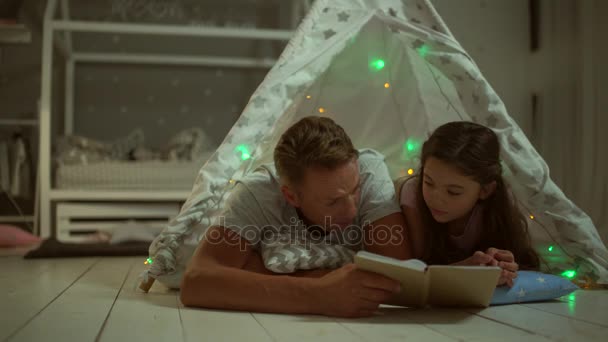 仁爱的父亲和他的女儿在家里读一本书 — 图库视频影像