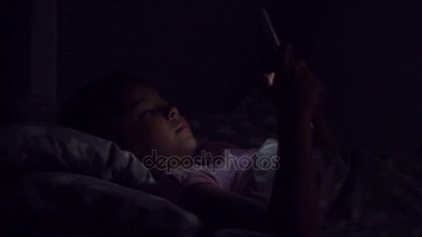 多莉的可爱的小女孩在床上使用她的平板张幻灯片 — 图库视频影像