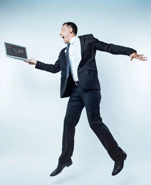Vzrušený muž podnikání skákání s notebookem přes pozadí — Stock fotografie