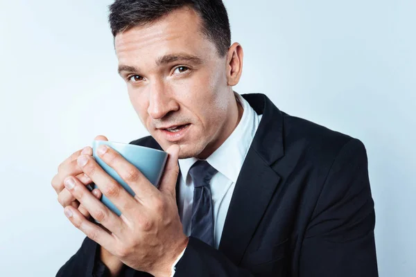 Close up of cold man in black suit drinking coffee — Stock Photo, Image