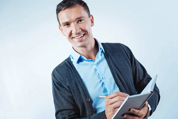 Friendly looking man with notebook smiling into camera — Stock Photo, Image