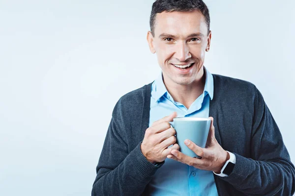 Веселый человек с чашкой кофе, сияющий перед камерой — стоковое фото