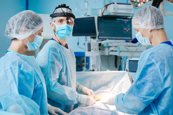 Tres doctores de pie alrededor de su paciente — Foto de Stock