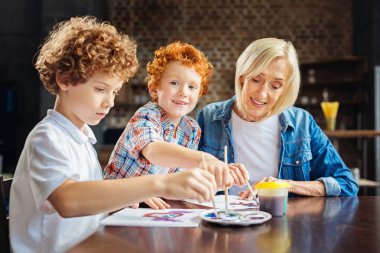Sevimli Kızıl saçlı çocuk boyama kardeşi ve büyükanne ile zevk