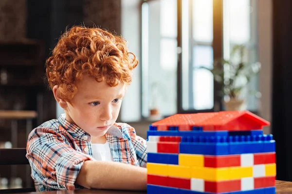 Concentrado menino de olhos azuis olhando para casa de brinquedo — Fotografia de Stock