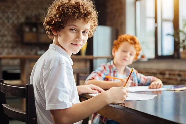 Slimme jongere op zoek naar de camera tijdens het tekenen met jongere broer — Stockfoto