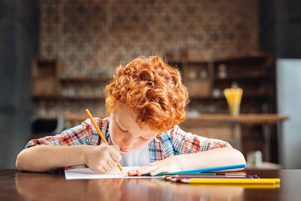 Redhead curly child drawing with colorful pencils