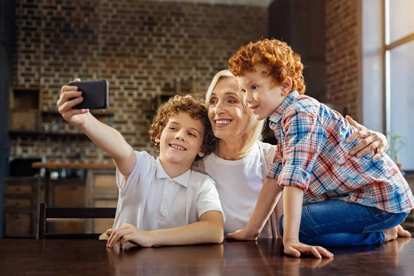 Netos tomando selfies com alegre avó — Fotografia de Stock