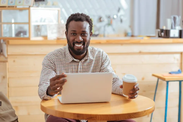 Smiling man adjusting angle of laptop screen — Stock Photo, Image