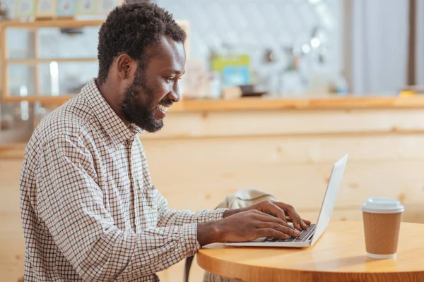 Kafede dizüstü bilgisayarda yazarak mutlu genç adam